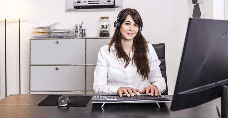Lisa Johner bei Ihrer Arbeit vor einem Bildschirm mit einem Headset auf dem Kopf